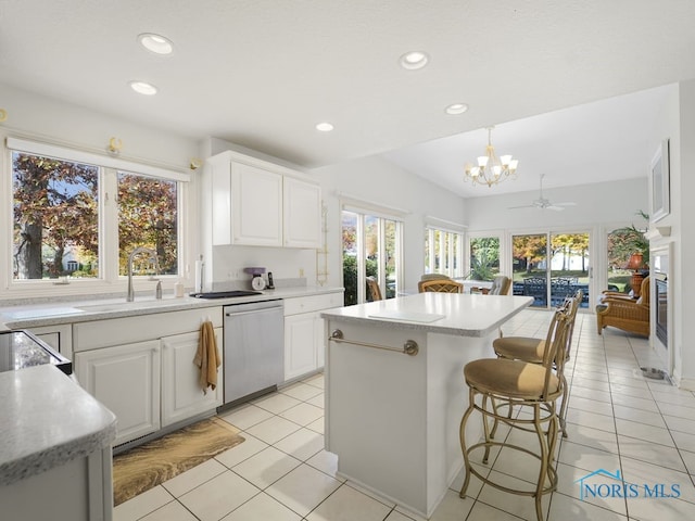 kitchen with hanging light fixtures, a kitchen island, white cabinetry, stainless steel dishwasher, and ceiling fan with notable chandelier