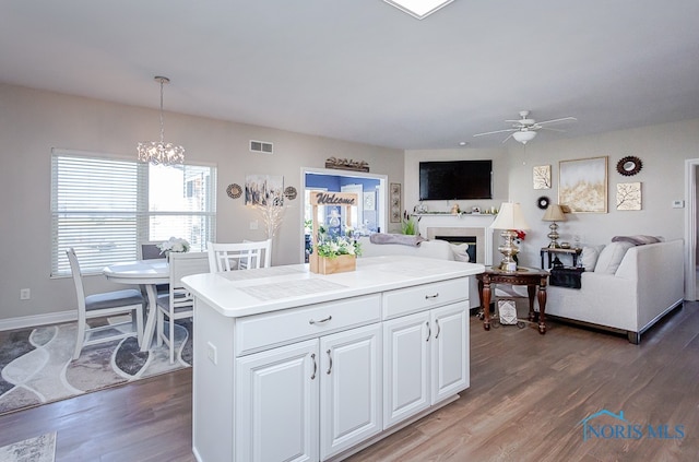 kitchen with white cabinets, a kitchen island, decorative light fixtures, ceiling fan with notable chandelier, and dark hardwood / wood-style flooring