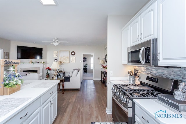 kitchen with ceiling fan, wood-type flooring, stainless steel appliances, tasteful backsplash, and white cabinetry