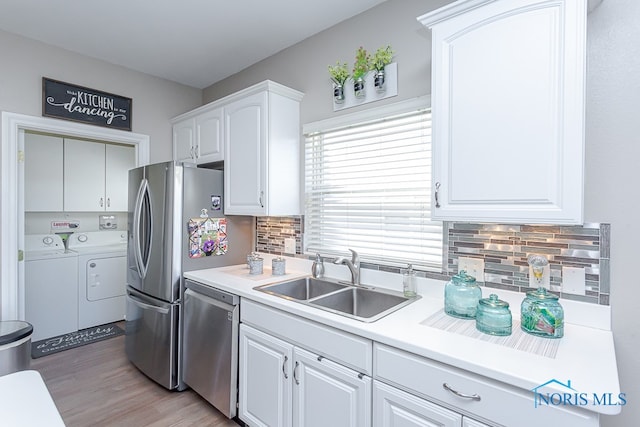 kitchen featuring independent washer and dryer, white cabinets, hardwood / wood-style flooring, sink, and dishwasher