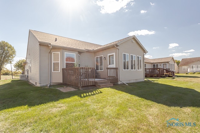 back of property with a wooden deck, cooling unit, and a lawn