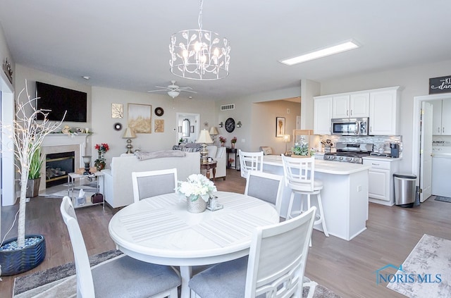 dining space featuring ceiling fan with notable chandelier and dark hardwood / wood-style floors