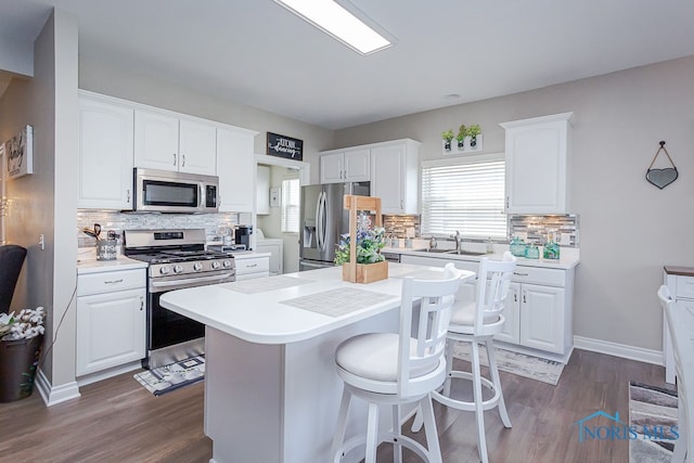 kitchen with appliances with stainless steel finishes, dark wood-type flooring, decorative backsplash, and white cabinetry