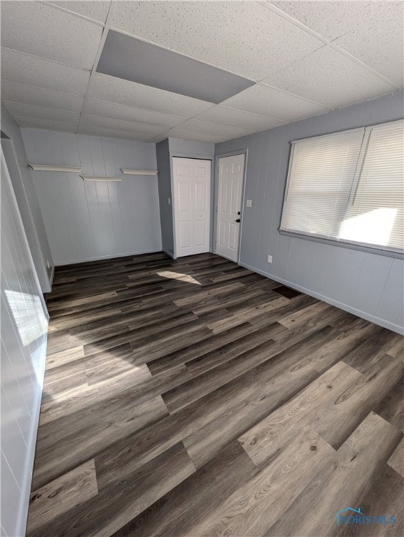 spare room with a drop ceiling and dark hardwood / wood-style flooring