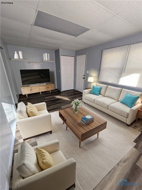 living room with a drop ceiling and wood-type flooring