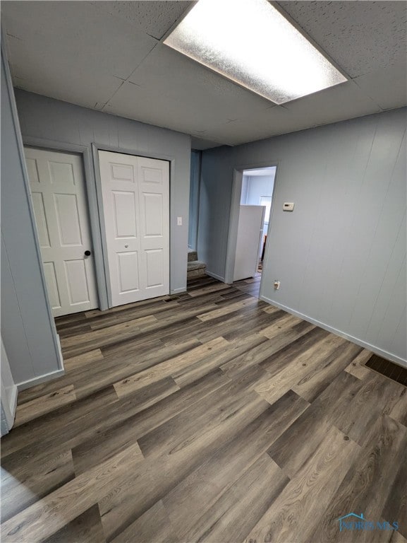 unfurnished bedroom with a paneled ceiling, a closet, and dark hardwood / wood-style flooring