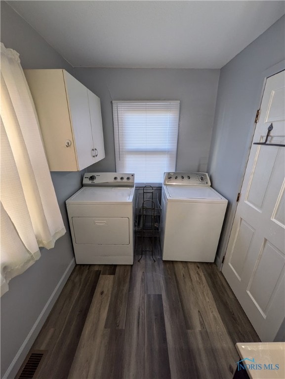 washroom with dark hardwood / wood-style floors, cabinets, and washer and clothes dryer