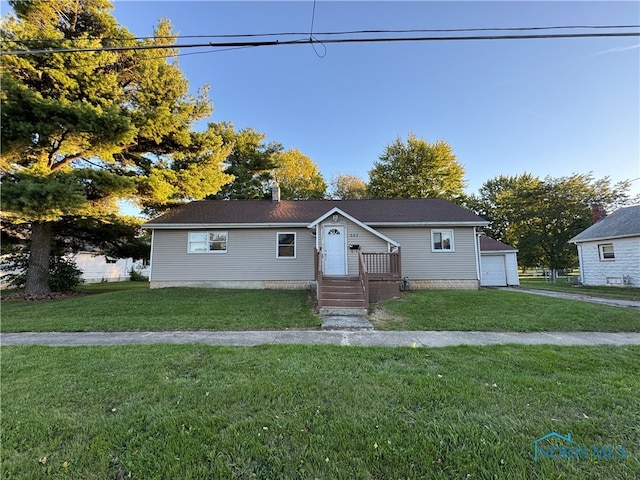 view of front of property featuring a front yard, a garage, and an outbuilding