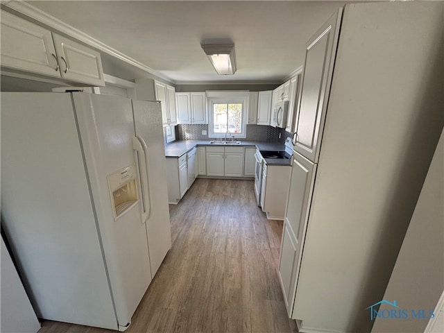 kitchen with tasteful backsplash, white appliances, light hardwood / wood-style flooring, sink, and white cabinets