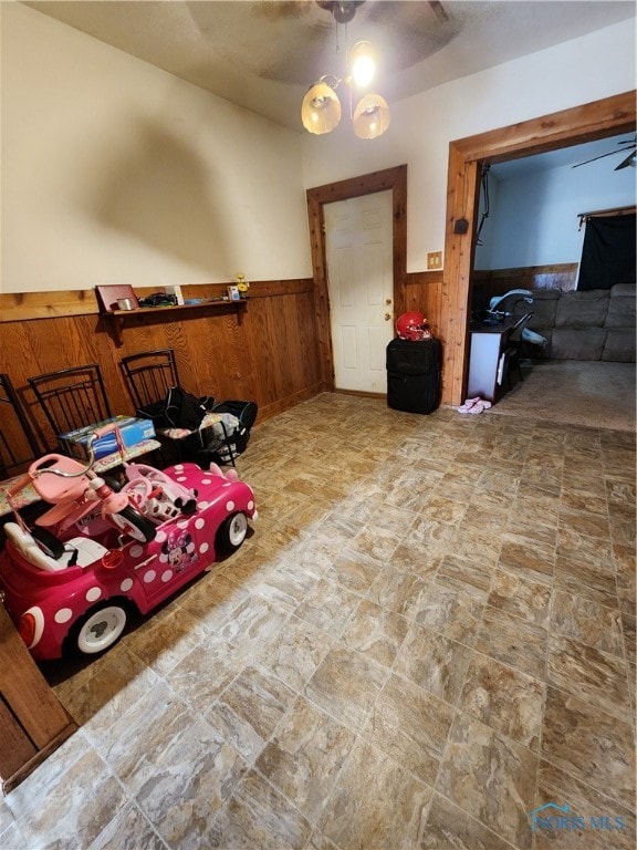 interior space with ceiling fan and wood walls