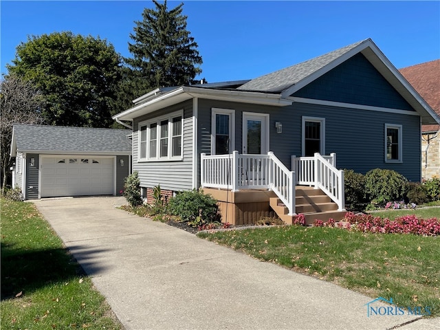 view of front of home featuring an outbuilding, covered porch, a front yard, and a garage