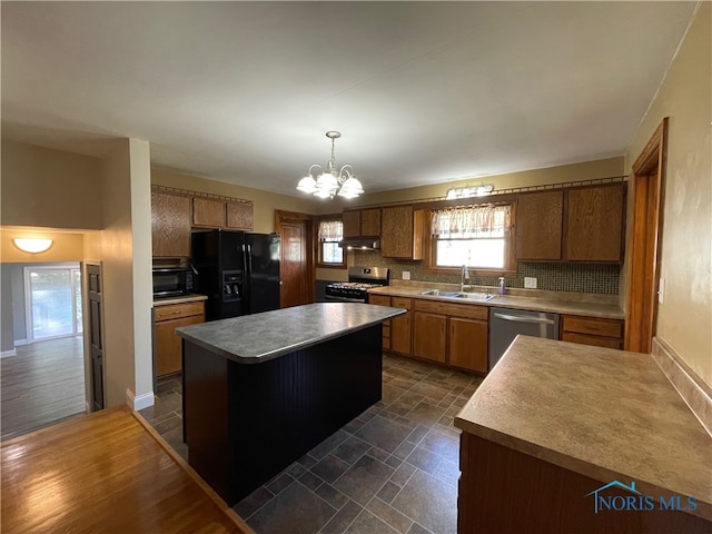 kitchen featuring sink, decorative light fixtures, appliances with stainless steel finishes, a center island, and decorative backsplash