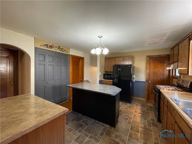 kitchen featuring pendant lighting, sink, black appliances, a center island, and a notable chandelier