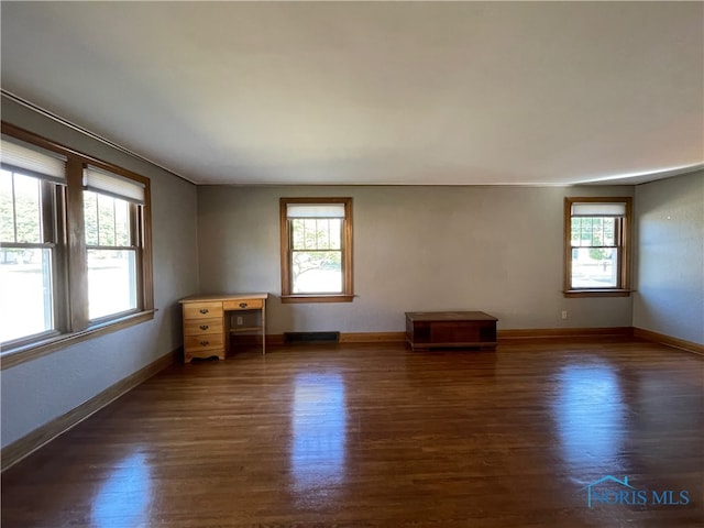 spare room featuring crown molding, a wealth of natural light, and dark wood-type flooring