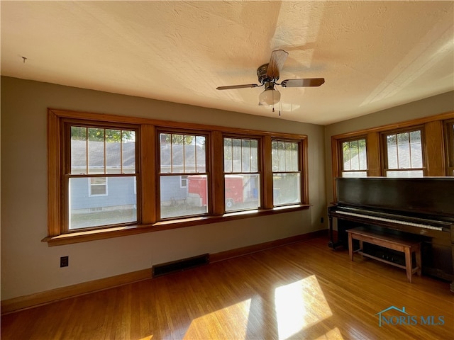 interior space featuring light wood-type flooring, ceiling fan, and a textured ceiling