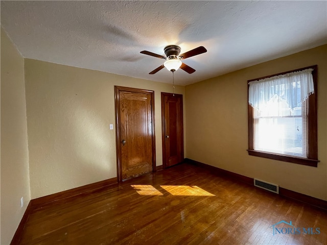 unfurnished bedroom featuring ceiling fan, dark wood-type flooring, and a textured ceiling