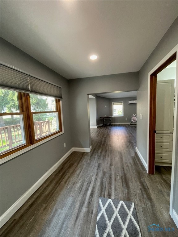 unfurnished living room with dark wood-type flooring and a wall mounted AC