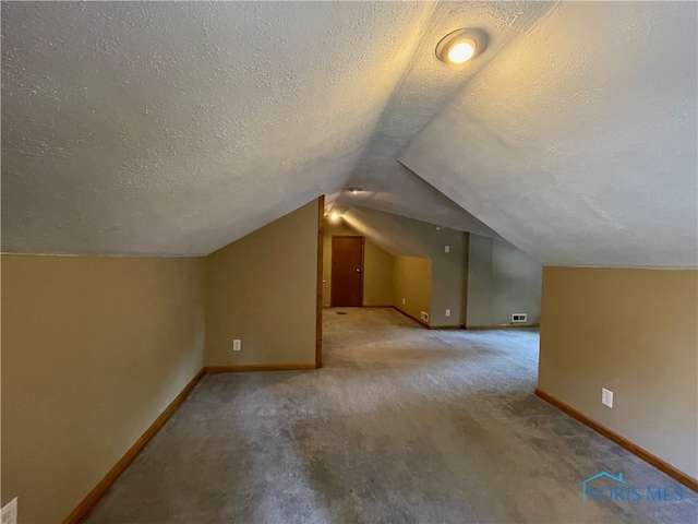 additional living space with lofted ceiling, carpet, and a textured ceiling