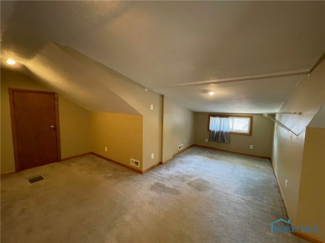 additional living space featuring lofted ceiling and light carpet