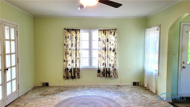 empty room with ornamental molding, ceiling fan, and carpet