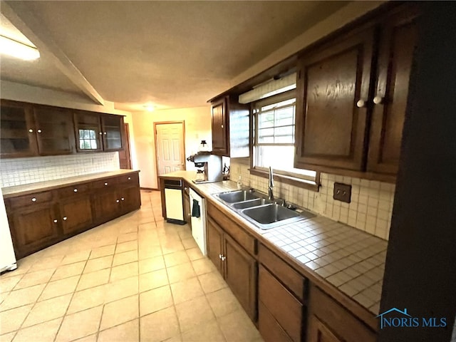 kitchen with sink, tile counters, dishwasher, backsplash, and light tile patterned floors