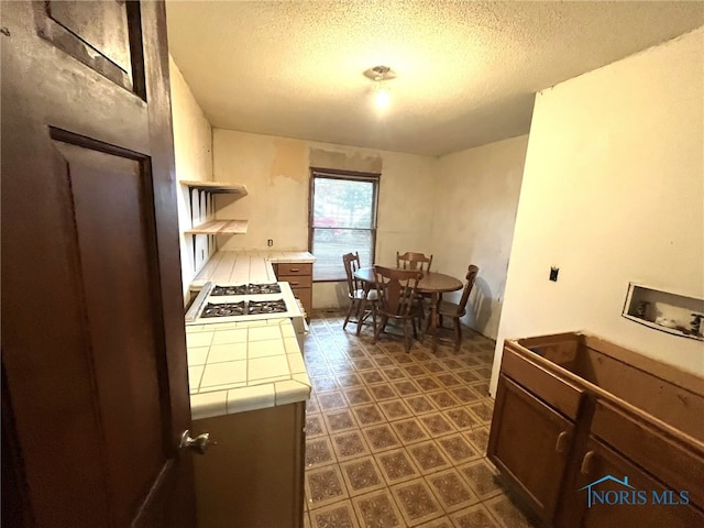 kitchen with tile countertops, white gas cooktop, and a textured ceiling