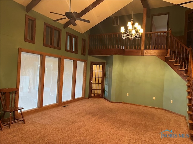 unfurnished living room with ceiling fan with notable chandelier, high vaulted ceiling, and carpet flooring