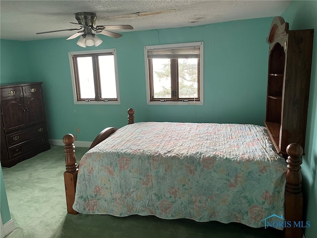 bedroom featuring ceiling fan, light colored carpet, and a textured ceiling