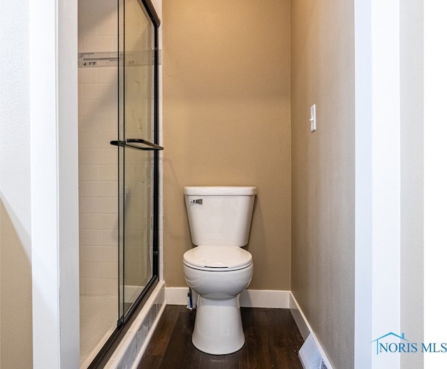 bathroom featuring a shower with shower door, toilet, and wood-type flooring