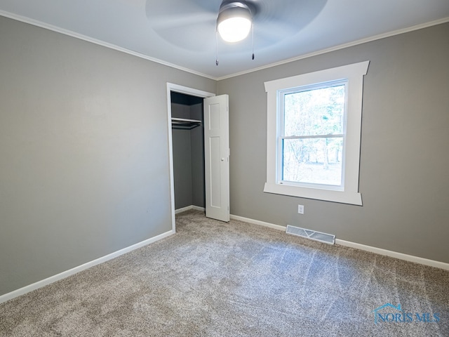 unfurnished bedroom featuring a closet, crown molding, carpet flooring, and ceiling fan