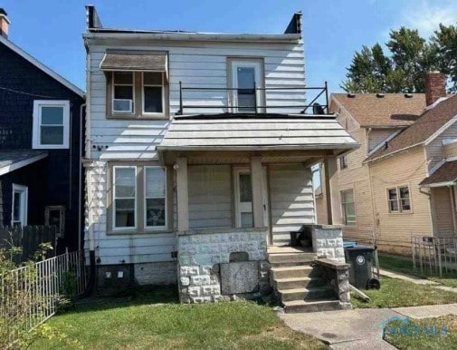 view of front facade featuring a front lawn, covered porch, and a balcony