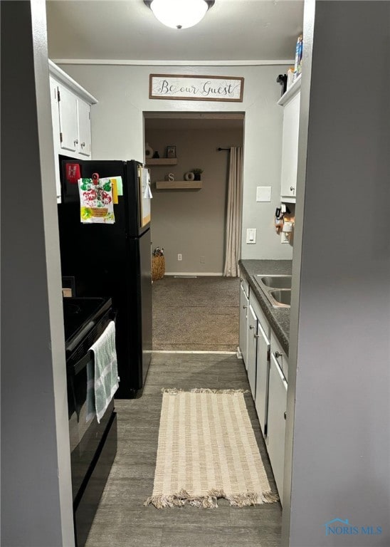 kitchen with sink, black range with electric cooktop, hardwood / wood-style floors, and white cabinetry