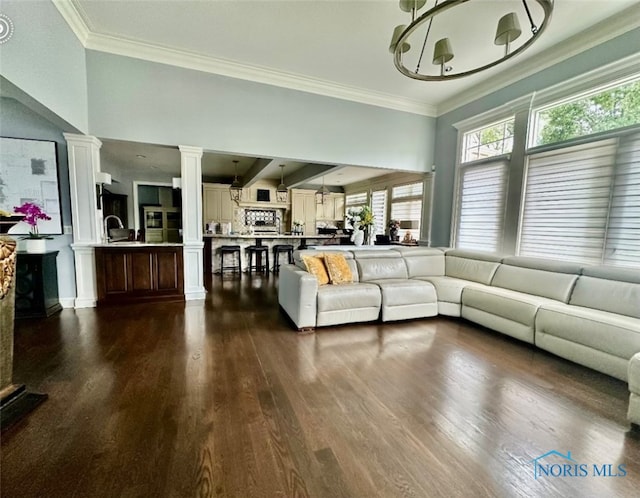 living room featuring ornate columns, crown molding, a chandelier, and dark hardwood / wood-style floors