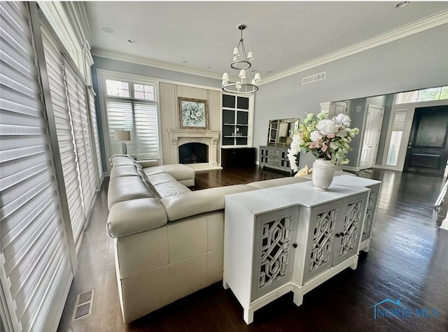 living room with dark wood-type flooring, ornamental molding, and an inviting chandelier