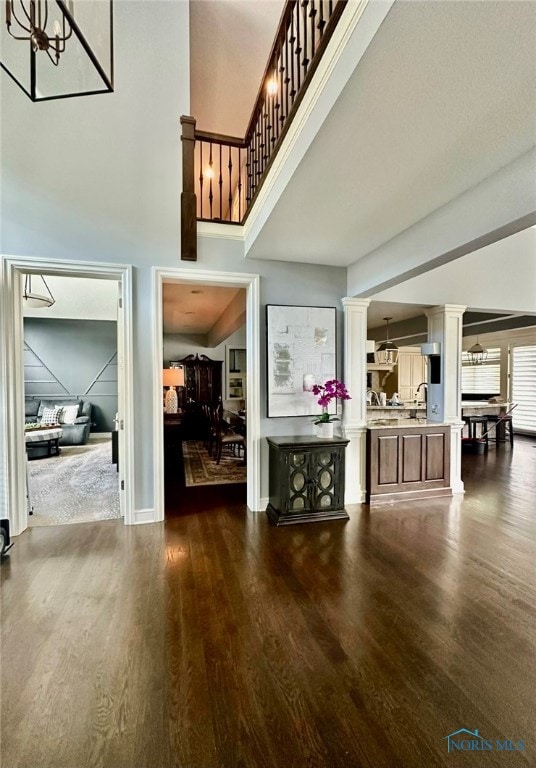 interior space with ornate columns, a high ceiling, dark hardwood / wood-style flooring, and an inviting chandelier