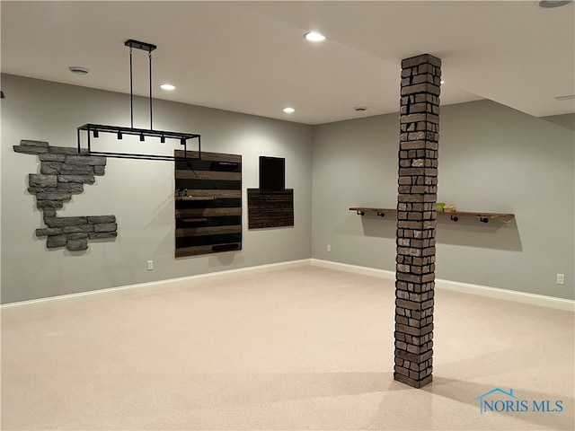 unfurnished living room featuring decorative columns and light colored carpet