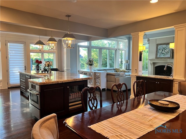 dining space featuring sink, decorative columns, a chandelier, and dark hardwood / wood-style flooring