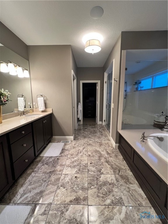 bathroom featuring vanity, shower with separate bathtub, and a textured ceiling