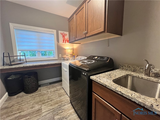 clothes washing area featuring sink, cabinets, and washer and clothes dryer