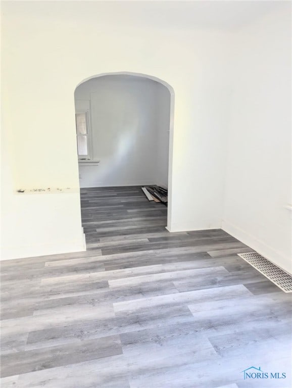 spare room with arched walkways, visible vents, and wood finished floors