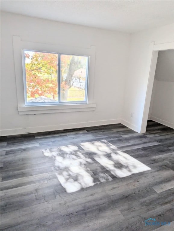 unfurnished room with dark wood-type flooring