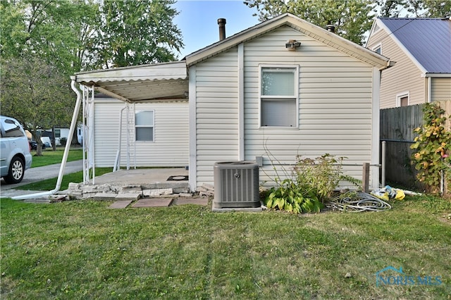 rear view of house featuring cooling unit and a yard