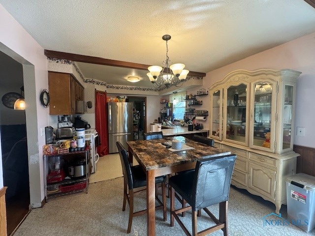 carpeted dining room with a chandelier and a textured ceiling