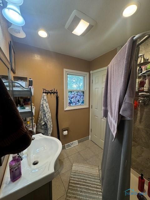 full bath featuring tile patterned floors, visible vents, baseboards, a shower with shower curtain, and vanity