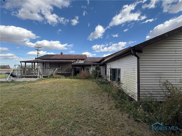 back of property with a wooden deck and a yard