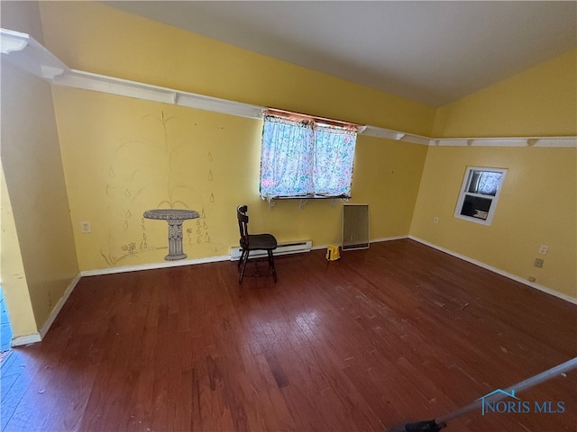 empty room featuring baseboard heating, hardwood / wood-style floors, a wealth of natural light, and vaulted ceiling