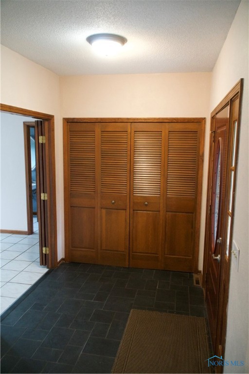 hallway with dark tile patterned floors and a textured ceiling