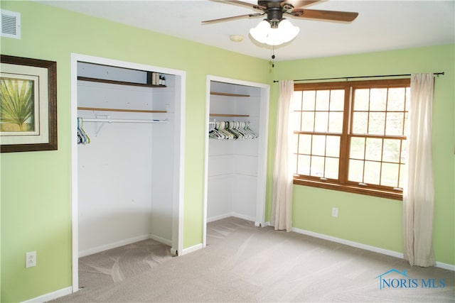 unfurnished bedroom with multiple closets, light colored carpet, and ceiling fan