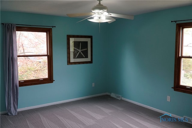 spare room with ceiling fan, light carpet, and plenty of natural light