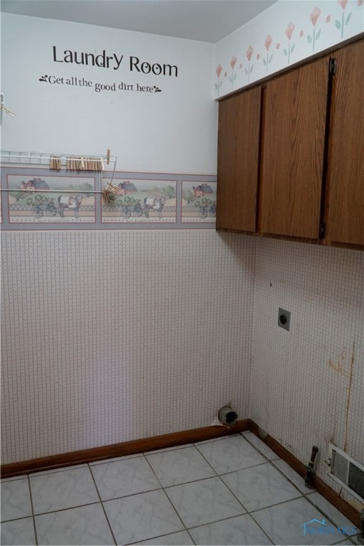 laundry area featuring hookup for an electric dryer, light tile patterned floors, and cabinets